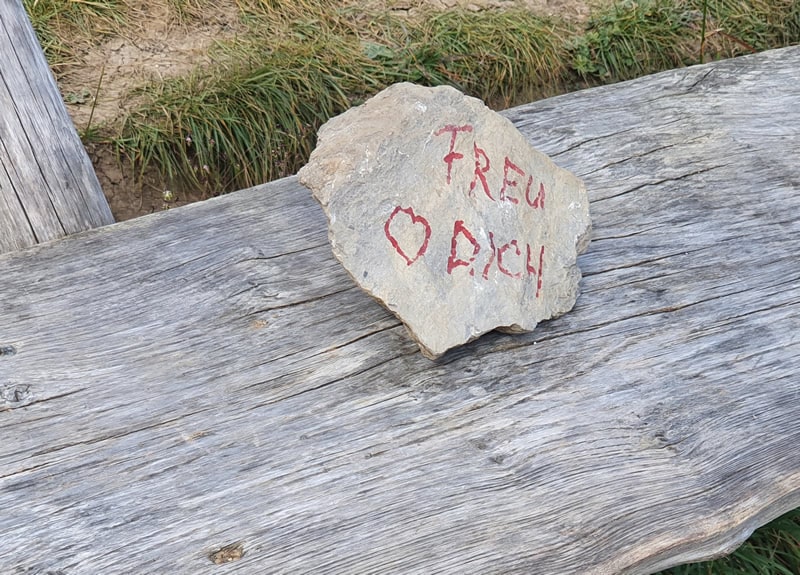 Ein Stein auf einer Bank, auf dem Freu dich steht.